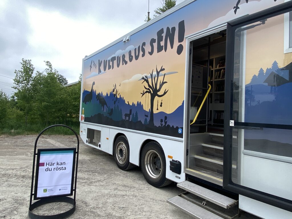 Lastbil målad med dinosaurielandskap och test som lyder Kulturbussen. En skylt där det står att du kan rösta här står placerad utanför.