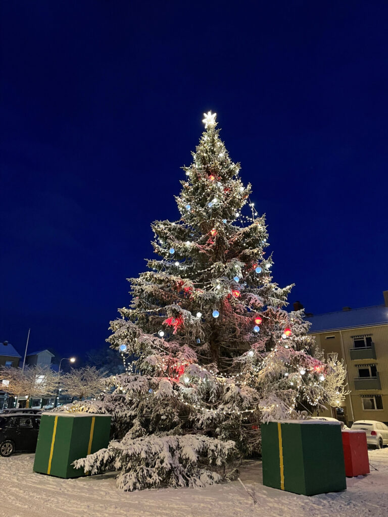 Gran på torg med snö på och stora paket under