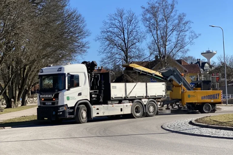 En stor lastbil med sopmaskin som kör på en gata